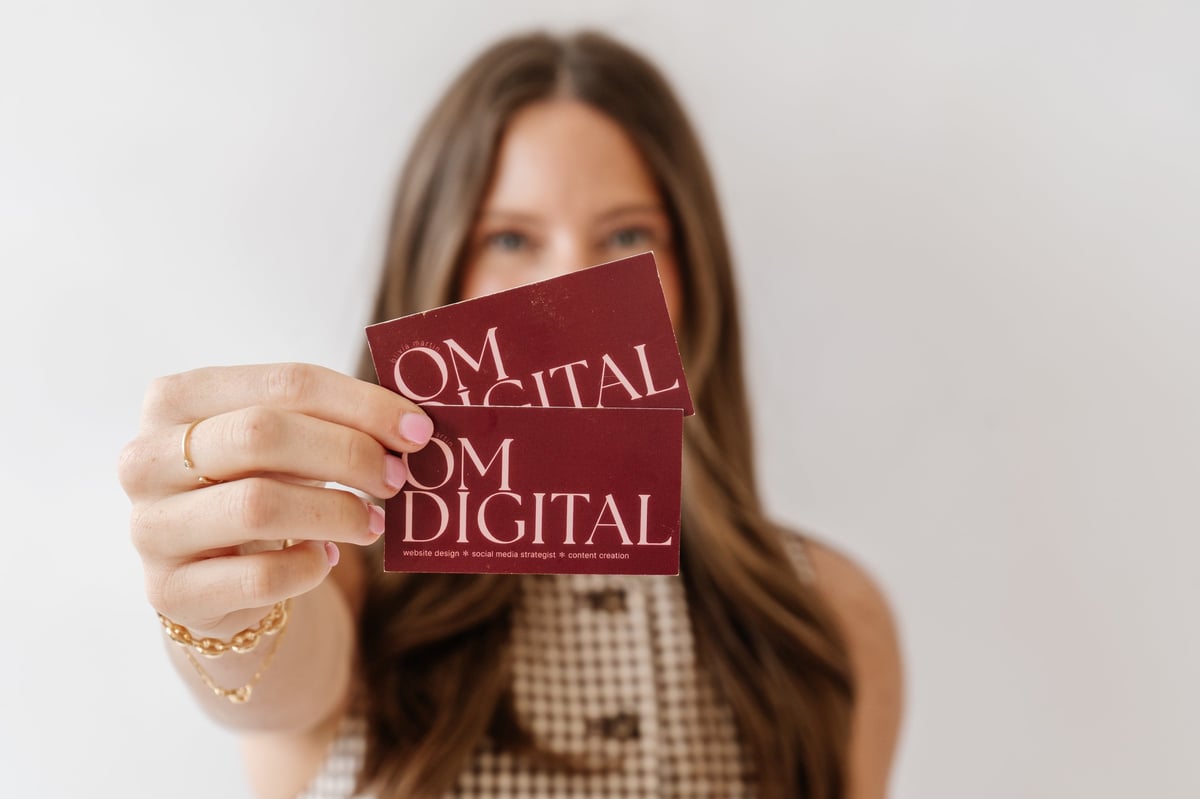 Woman holding a burgundy business card with From Digital text, smiling at camera