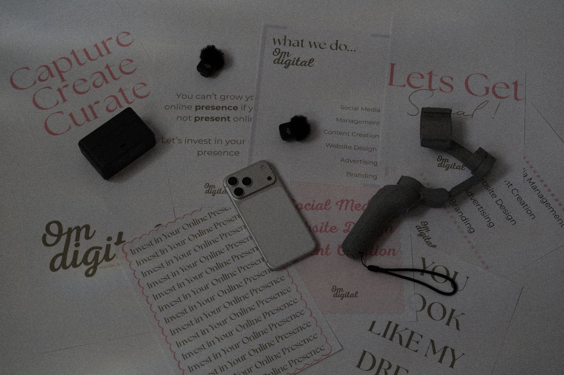Flat lay of marketing and branding materials including printed cards with text, small objects, and a phone on white surface