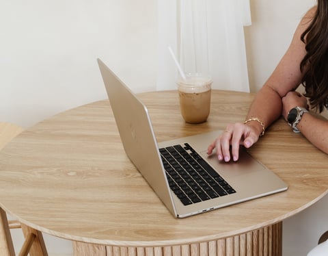 Creative workspace with laptop and iced coffee at wooden desk